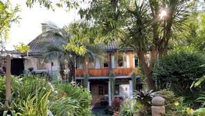 A two-story house with a garden entrance, surrounded by various plants and trees. - modern Loft in historic Villa with beautiful gardens (Quito)