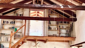A spacious loft with high ceilings, exposed wooden beams, and a mezzanine level with bookshelves. - modern Loft in historic Villa with beautiful gardens (Quito)