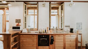 A kitchen with wooden cabinets, a microwave, a toaster, a kettle, and a sink. - modern Loft in historic Villa with beautiful gardens (Quito)
