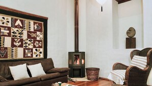 A cozy living room with a brown sofa, a wicker chair, a wooden coffee table, and a fireplace. - modern Loft in historic Villa with beautiful gardens (Quito)