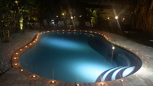Une piscine bordée de briques et illuminée sur son pourtour.