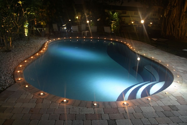 A swimming pool with a brick border and lights around it.