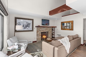A modern living room with a stone fireplace, a television mounted above it, and a comfortable sofa.