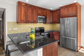 A kitchen with wooden cabinets, stainless steel appliances, and a black countertop.
