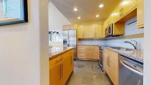 A modern kitchen with wooden cabinets, stainless steel appliances, and a granite countertop. - Landmark 503 - 3 Bedroom - Prime Lionshead Location, Ski Access, Mountain Views, (Vail)