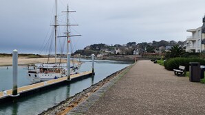 Un canal estrecho con un velero amarrado, una senda a lo largo y edificios residenciales al fondo.