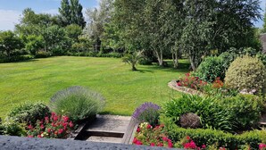 Un jardín bien cuidado con césped, arbustos diversos y plantas con flores.