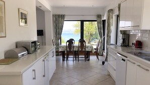 Una cucina con tavolo e sedie, una macchina da caffè e vista sul mare.