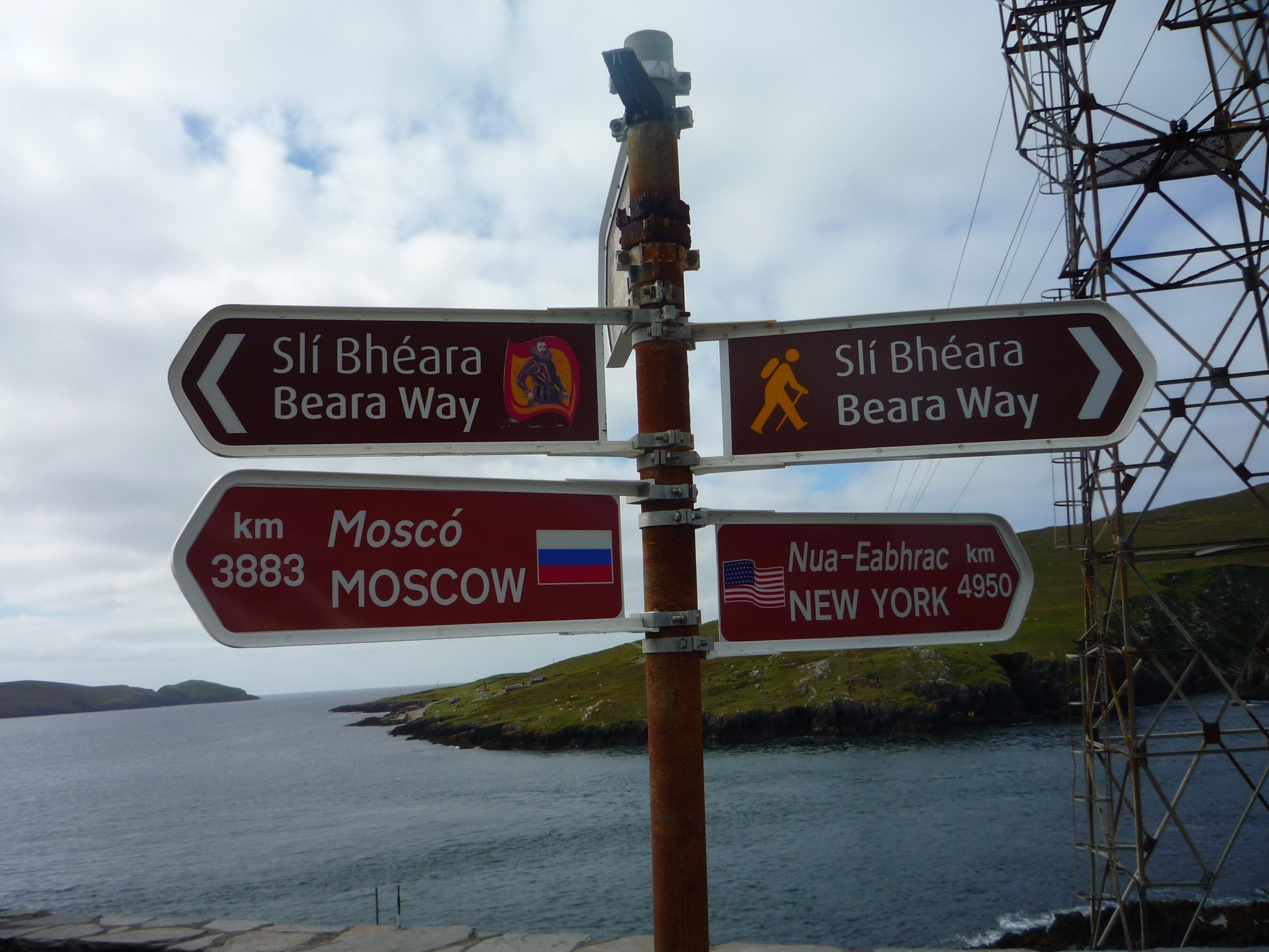 A directional signpost with arrows pointing to Slí Bhéara Beara Way and distances to Moscow and New York.