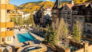 A hotel with a pool area, multiple buildings, and a mountainous backdrop. - Landmark 114 - 1 Bedroom Platinum (Vail)