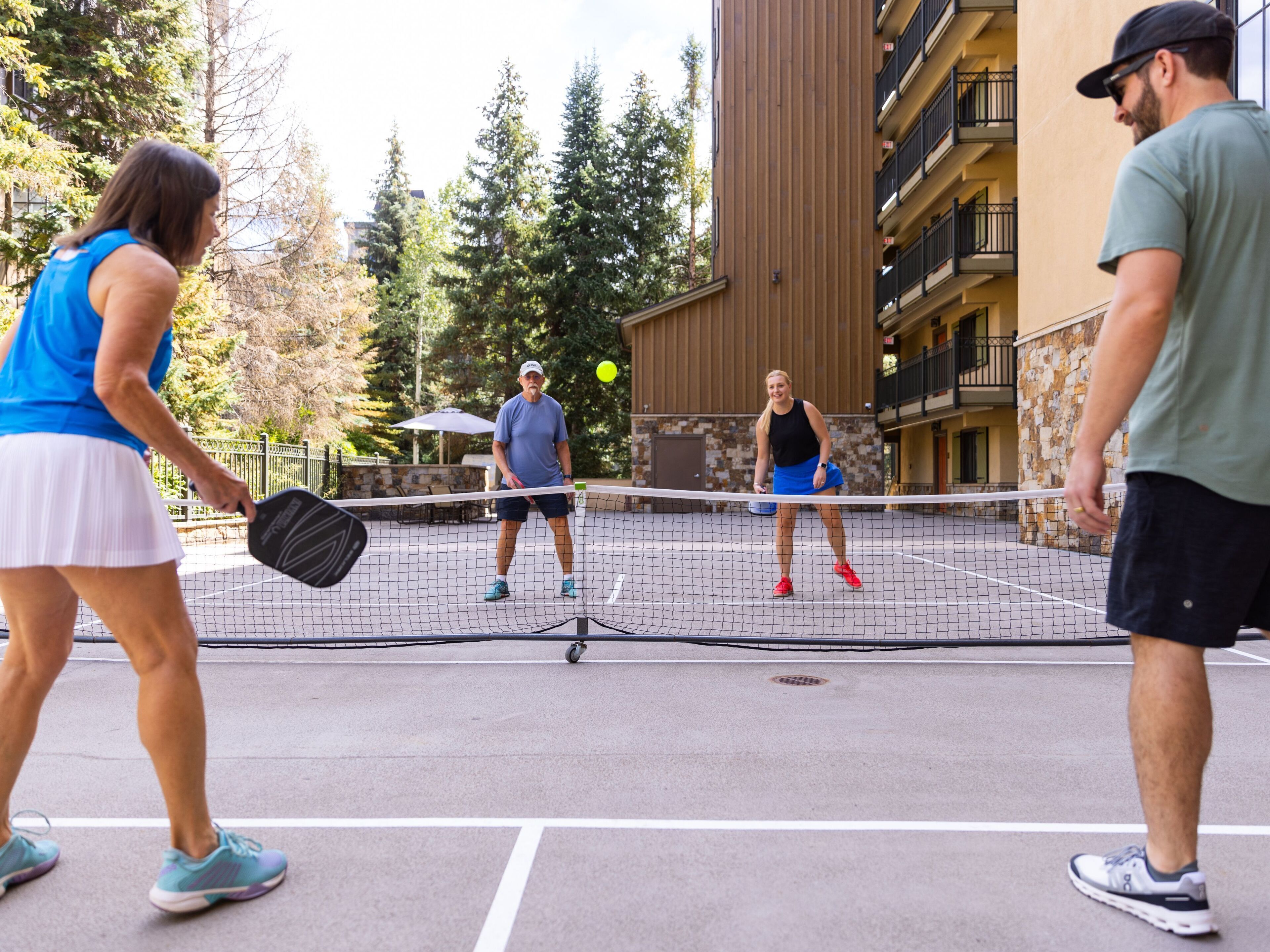 Un court de tennis avec des joueurs, un filet et un bâtiment en arrière-plan.