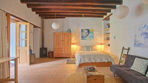 Une chambre confortable avec un lit en bois, un canapé, une commode en bois et un grand tableau accroché au mur.