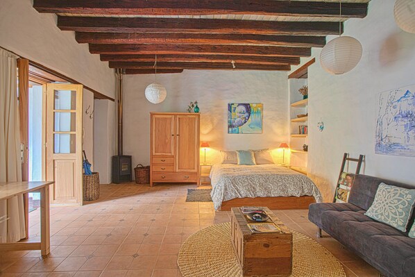 A cozy bedroom with a wooden bed, a sofa, a wooden chest of drawers, and a large painting on the wall. - Suite Tortuga with Beautiful Gardens in Historical Quito (Quito)