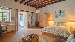 Une chambre confortable avec un grand lit, des poutres apparentes, un bureau et une fenêtre avec des rideaux.