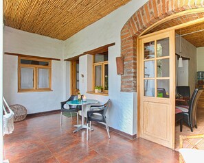 A room with a tiled floor, a round table with chairs, a window with wooden shutters, and a brick wall. - Suite Tortuga with Beautiful Gardens in Historical Quito (Quito)