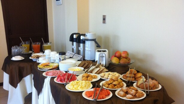 A buffet table with various breakfast items including fruits, pastries, and hot beverages. - El Prado Hotel (Cochabamba)