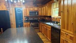 A kitchen with wooden cabinets, a granite countertop, stainless steel appliances, and a black dishwasher.