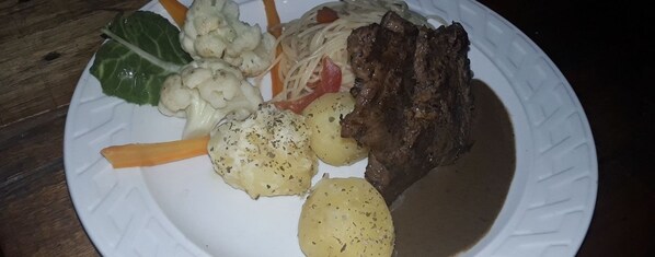 Une assiette contenant un steak, du chou-fleur, des carottes et des pommes de terre.