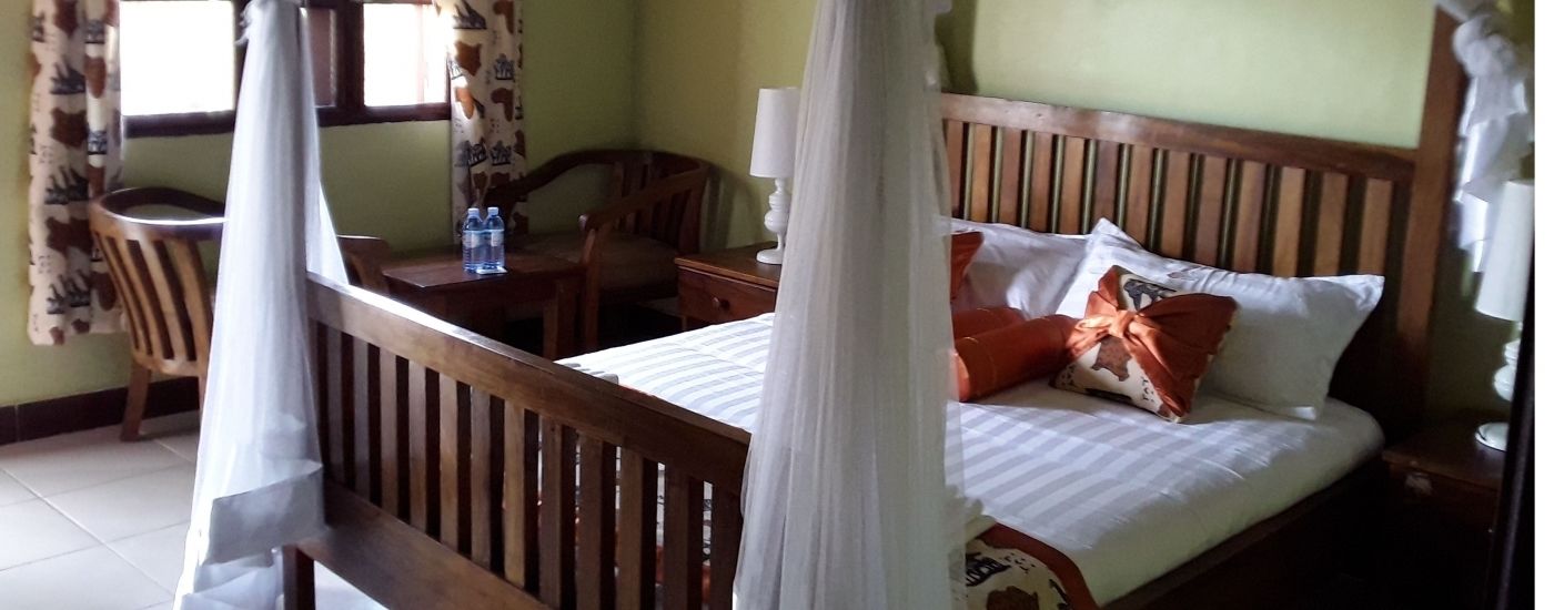 A bedroom with a wooden bed, a nightstand, a chair, and a desk with a lamp.