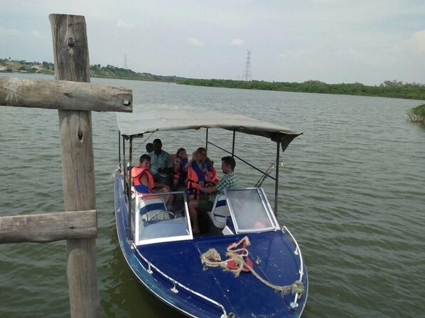 A boat with passengers wearing life jackets, docked at a wooden pier.
