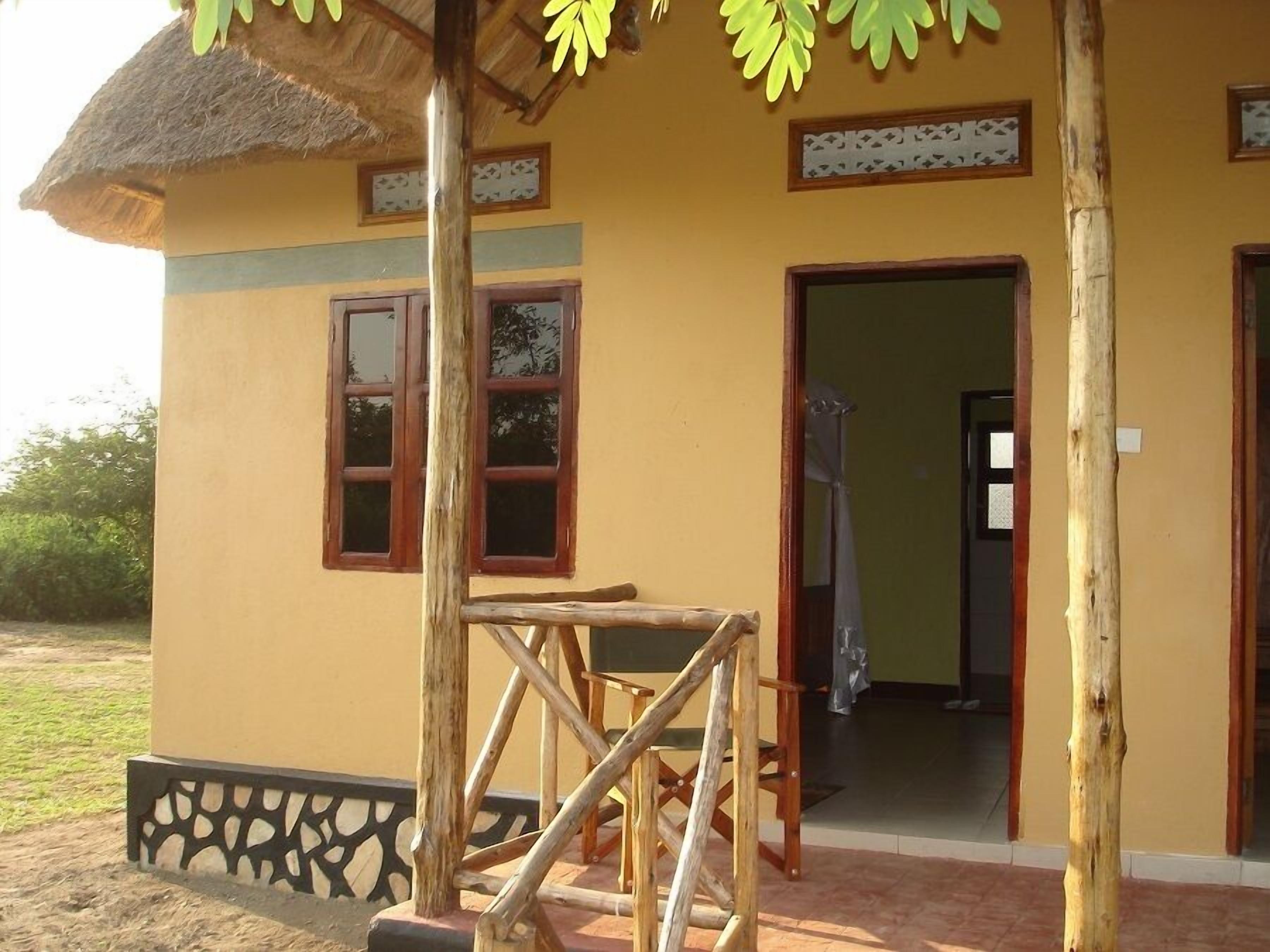 A yellow building with a thatched roof, wooden furniture, and a small table.