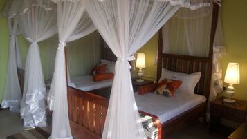 Habitación doble con dos camas, cada una con ropa de cama blanca y almohadas naranjas. Hay dos mesitas de noche con lámparas. La habitación tiene un cabecero de madera y suelo de madera.