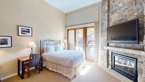 A bedroom with a large bed, a desk with a chair, a fireplace, and a balcony with a view. - Landmark 213 - 3 Bedroom Platinum (Vail)