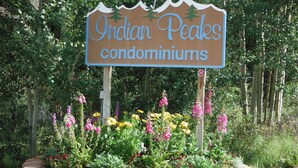 A sign for Indian Peaks condominiums surrounded by a landscaped garden with various flowers.