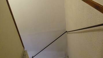 A staircase with a handrail, a painting of a candle and rocks, and a textured wall.