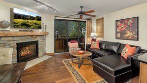 A living room with a fireplace, leather sofa, and a television mounted on the wall. - Landmark 120 - 1 Bedroom Platinum (Vail)