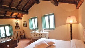 A bedroom with a bed, a dresser, a lamp, and a window with shutters.