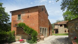 A rustic brick building with a small balcony and a stone wall.