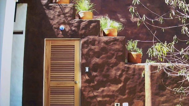 A wooden door with a window, a wall-mounted mailbox, and several potted plants. - Suite Luna with a beautiful garden in Historical Quito (Quito)