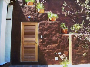 A wooden door with a window, a wall-mounted mailbox, and several potted plants. - Suite Luna with a beautiful garden in Historical Quito (Quito)