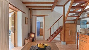 A cozy interior with a wooden staircase, a central table with fruit, and a wood-burning stove. - Suite Luna with a beautiful garden in Historical Quito (Quito)