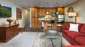 Una cocina moderna con armarios de madera, una isla central y un sofá rojo en una sala de estar.