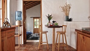 A kitchen with wooden furniture, a water dispenser, and a dining area with chairs and a table. - Romantic Cottage in a beautiful garden in  the Historic  Center of Quito (Quito)