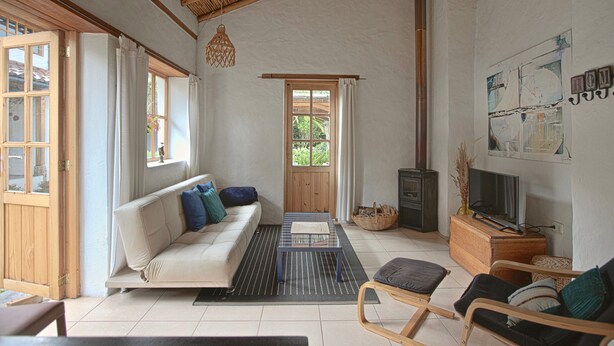 A living room with a sofa, a coffee table, a television, and a wooden cabinet. - Romantic Cottage in a beautiful garden in  the Historic  Center of Quito (Quito)