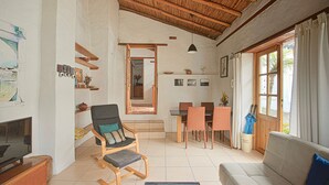 A spacious living area with a wooden ceiling, a sofa, a dining table with chairs, and a television. - Romantic Cottage in a beautiful garden in  the Historic  Center of Quito (Quito)