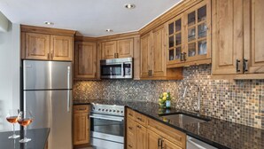 Una cocina moderna con armarios de madera, electrodomésticos de acero inoxidable y un salpicadero de mosaicos.