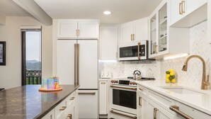 Une cuisine moderne avec des meubles blancs, un plan de travail noir et des appareils électroménagers en acier inoxydable.