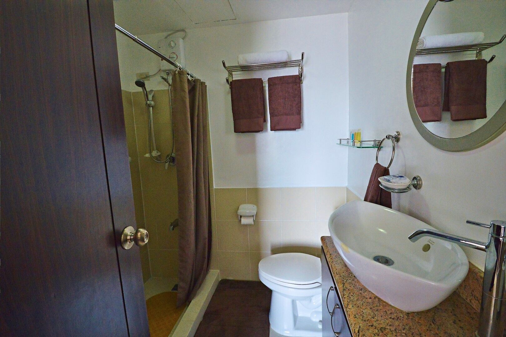 Une salle de bain équipée d’une douche, de toilettes, d’un lavabo et de deux serviettes accrochées au mur.