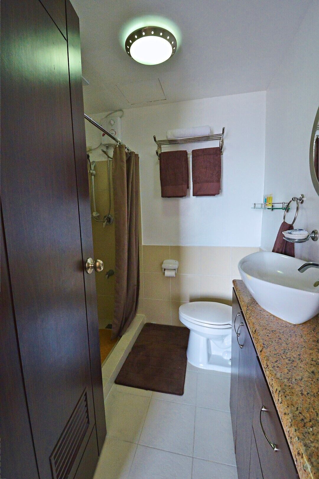 A bathroom with a shower, toilet, sink, and a towel rack with two towels.