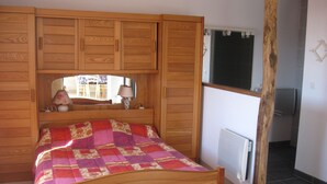 Une chambre à coucher avec un lit en bois, une fenêtre donnant sur un beau paysage et une armoire en bois.