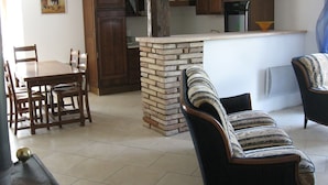 Una cocina rústica con una isla de ladrillo, armarios de madera y un comedor con mesa y sillas.