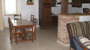 Un comedor con mesa y sillas de madera, una cocina con armarios de madera y una chimenea de ladrillo.