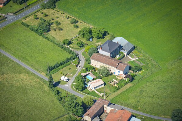 An aerial view of a rural property with a main house, a smaller attached building, and a swimming pool.