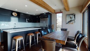 Una cocina moderna con una isla central, taburetes de bar y una mesa de comedor con sillas.