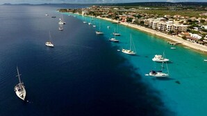 An aerial view of a coastal area with a marina, boats, and a hotel with multiple buildings along the shore.