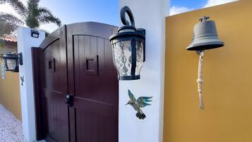 A gated entrance with a dark brown door, a decorative wall-mounted lantern, and a wall-mounted bell.